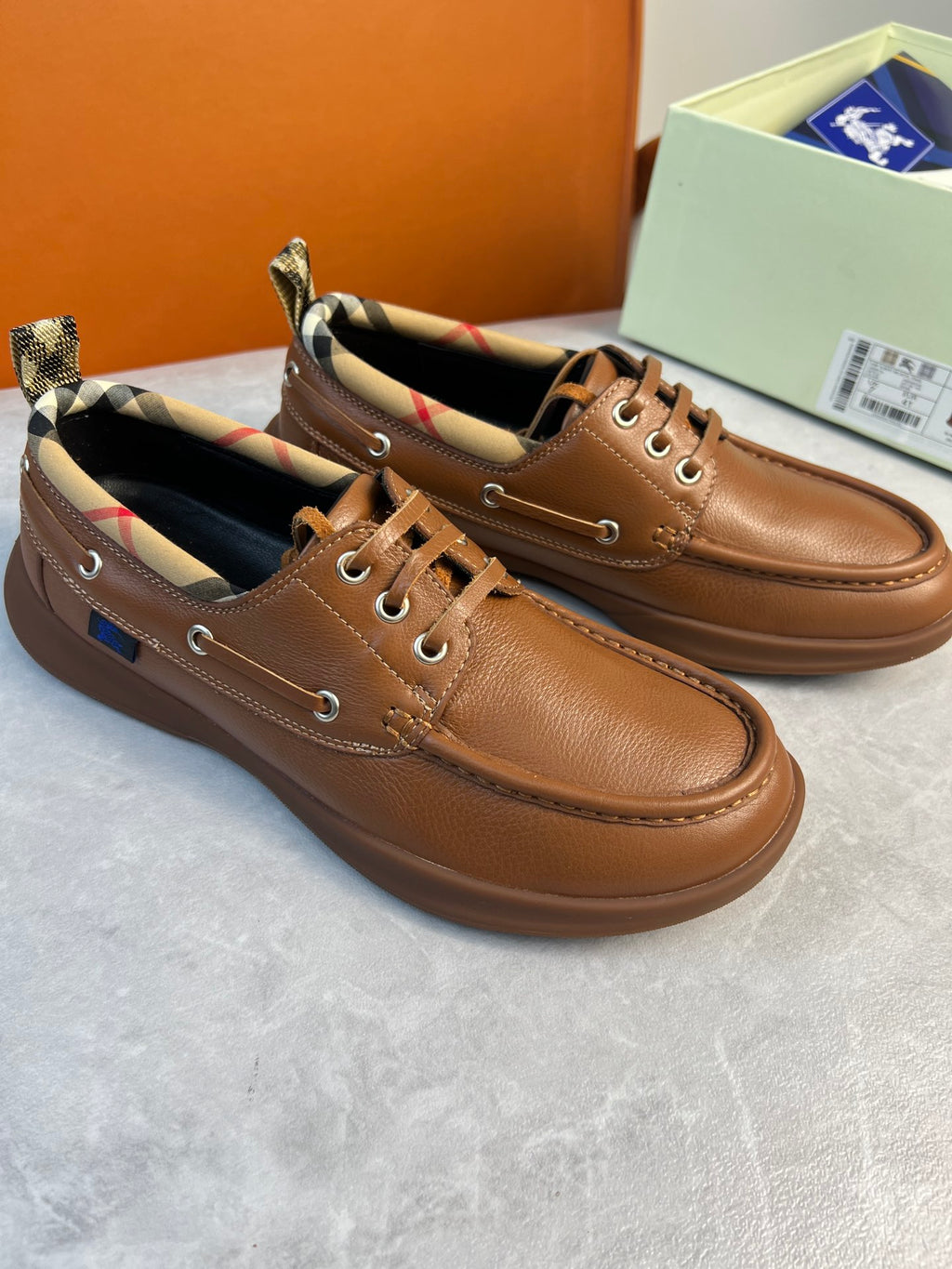 Burberry brown leather lace-up boat shoes shown from side view with checkered collar lining