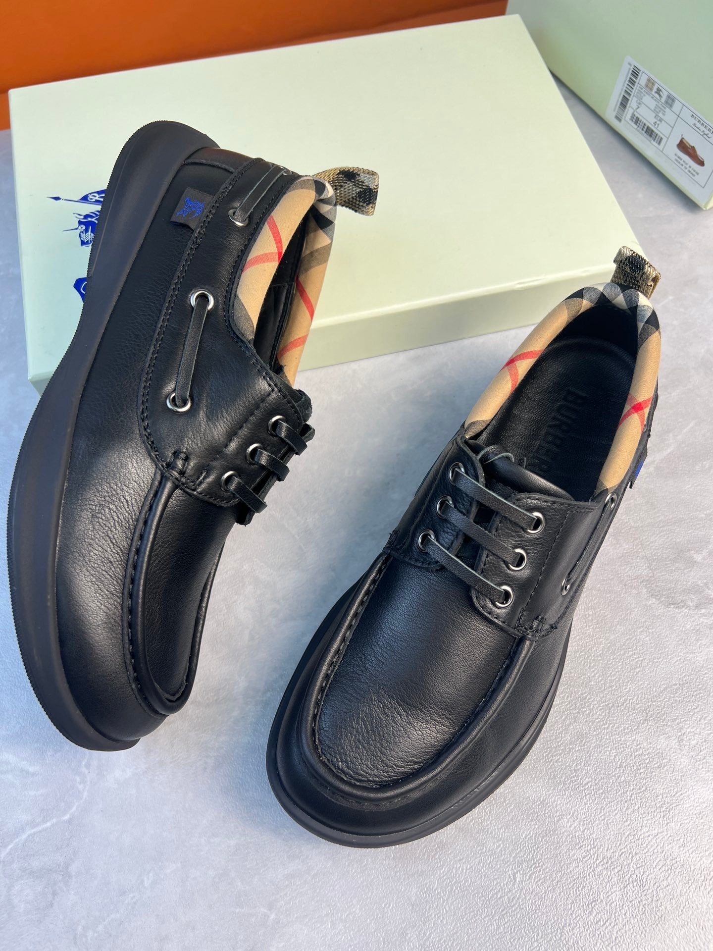 Black lace-up leather shoes showing plaid interior lining at the collar