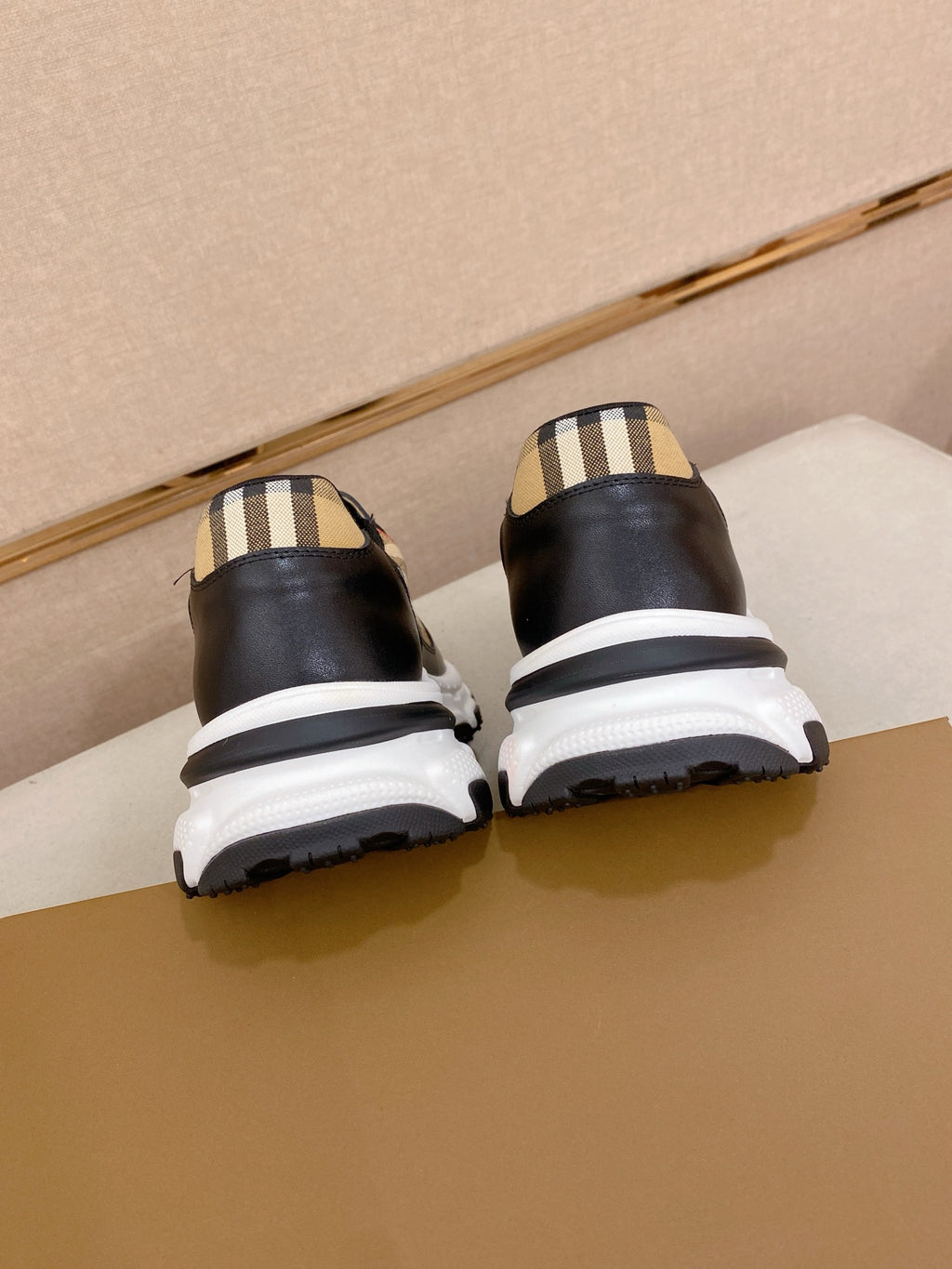 Burberry sneakers back view, black uppers with plaid heel detail and white midsole