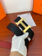 Hermes belt detail with gold-tone H buckle on dark textured leather strap