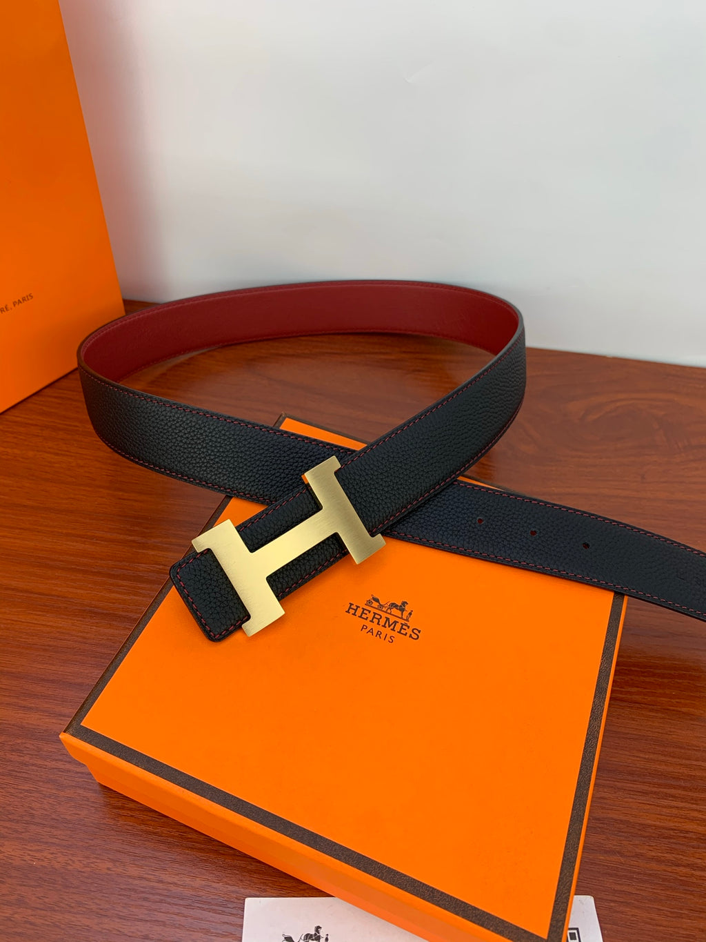Hermes belt on orange box with gold-tone H buckle and dark textured strap