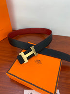 Hermes belt on orange box with gold-tone H buckle and dark textured strap