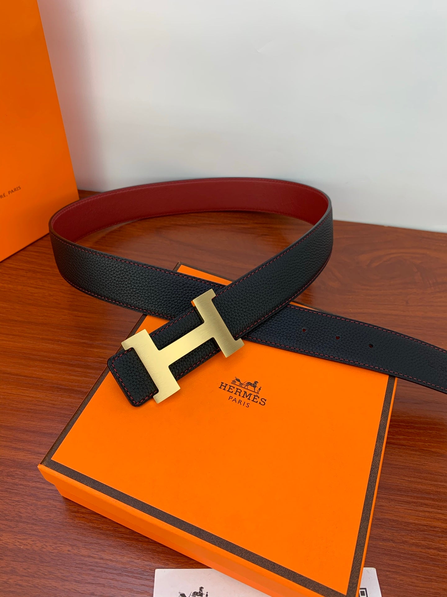 Hermes belt on orange box with gold-tone H buckle and dark textured strap
