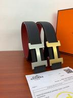 Hermes reversible belt rolled up: dark leather with gold-tone H buckle and red lining