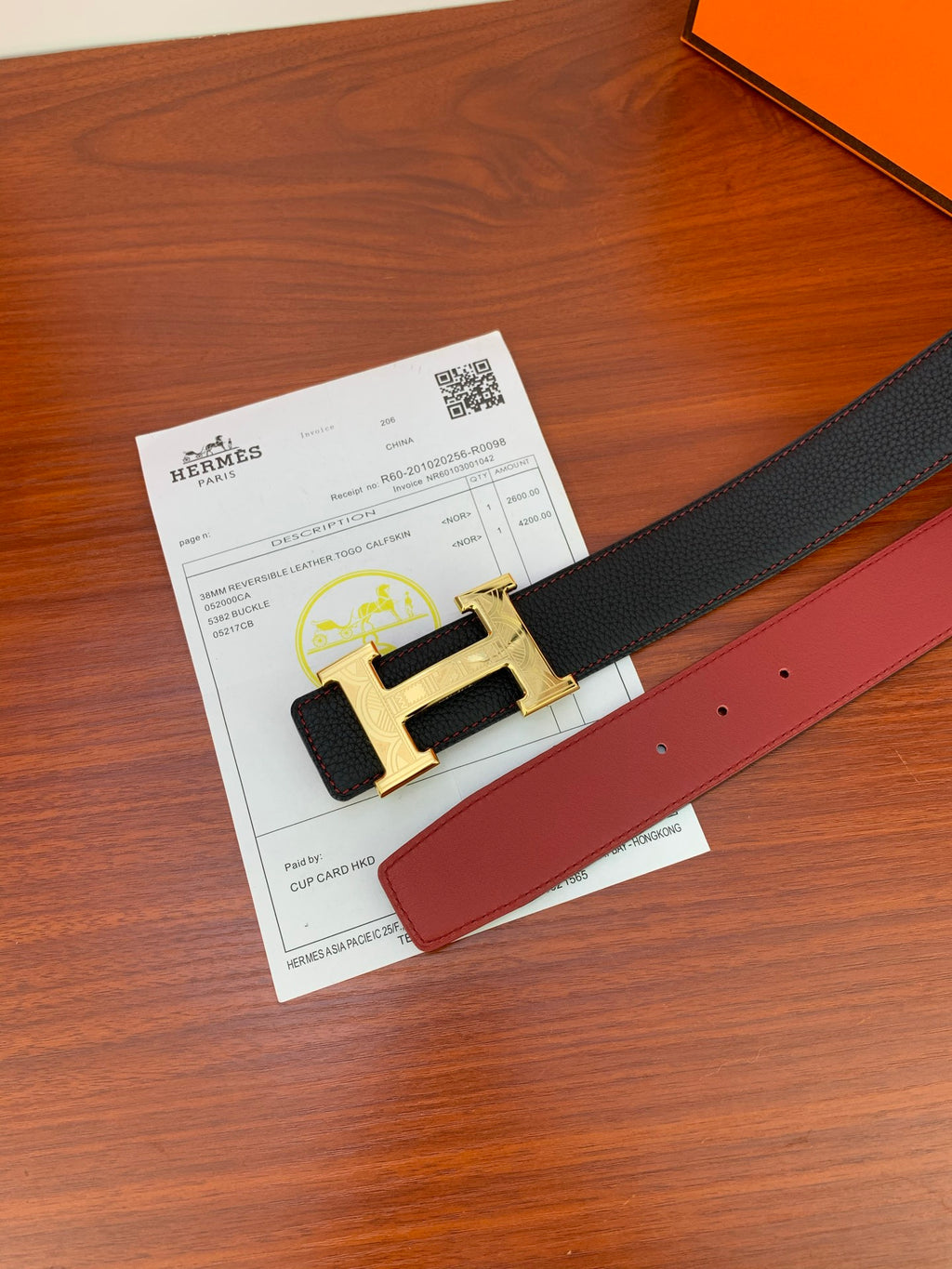 Hermes belt with gold-toned H buckle and dark strap with red inner lining