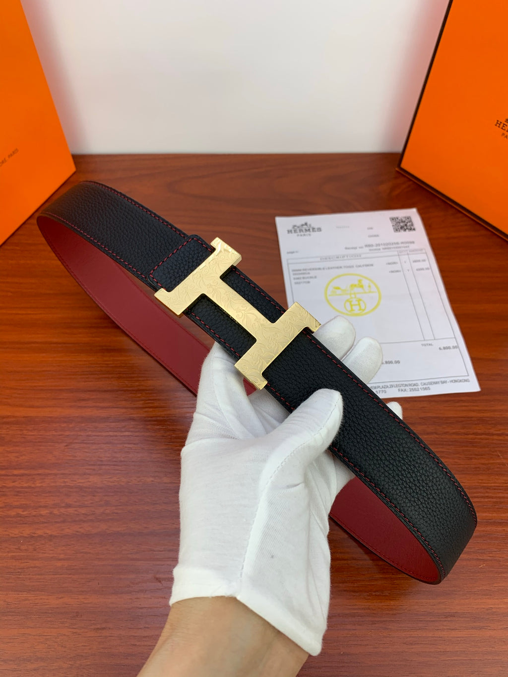 Hermes leather belt, black textured strap with gold H buckle and red underside