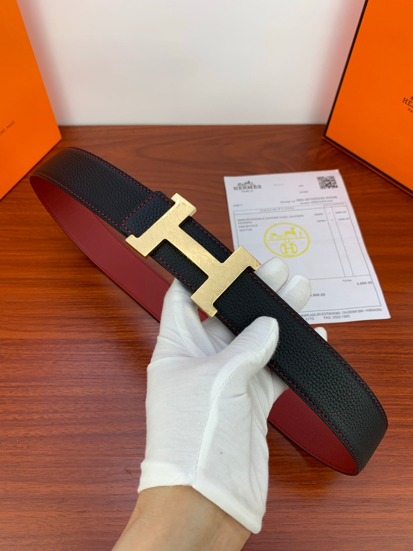 Hermes leather belt, black textured strap with gold H buckle and red underside
