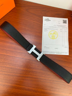 Hermes belt lying flat: black textured strap with gold buckle and red reverse