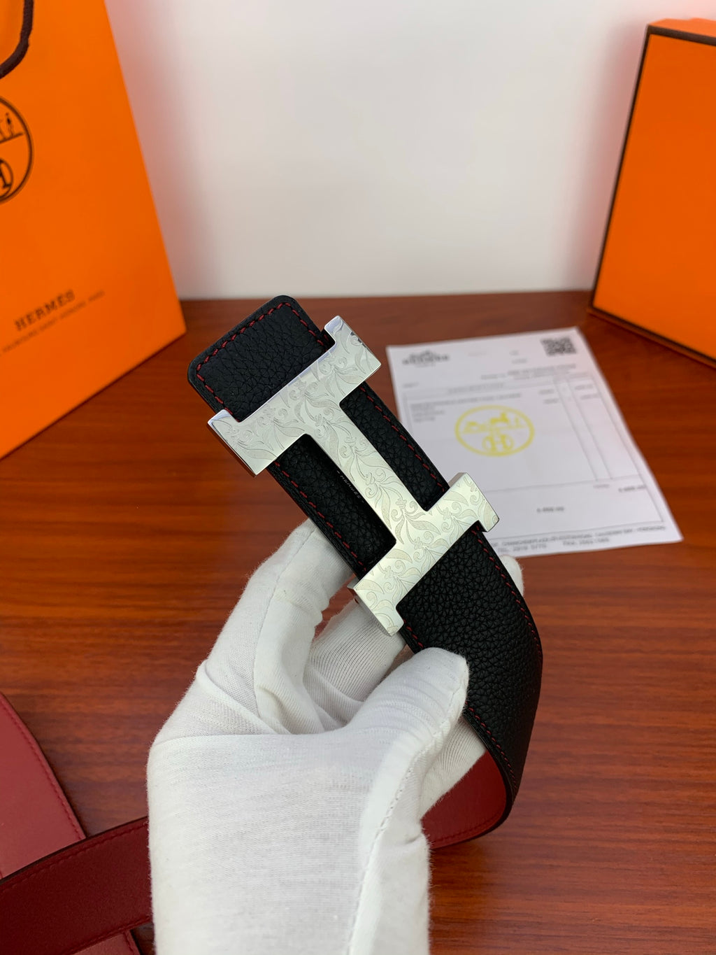 Hermes belt in hand: black strap with gold buckle and red underside
