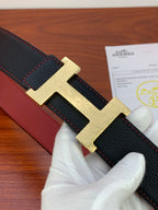 Hermes belt detail: black textured leather strap with red stitching and gold buckle