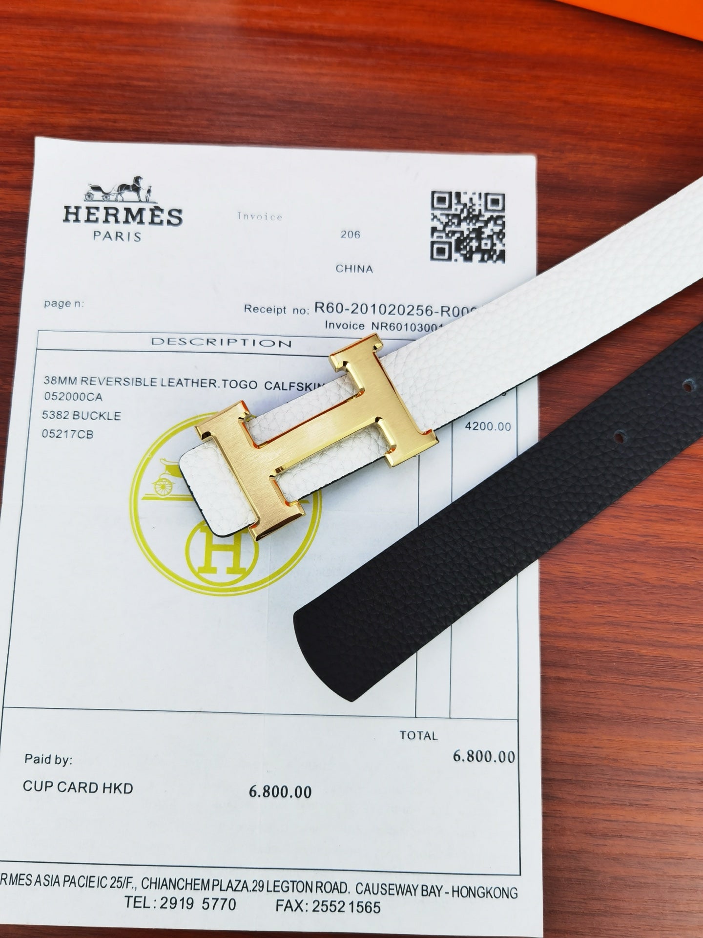 Hermes belt detail with black reversible leather and gold buckle on light strap