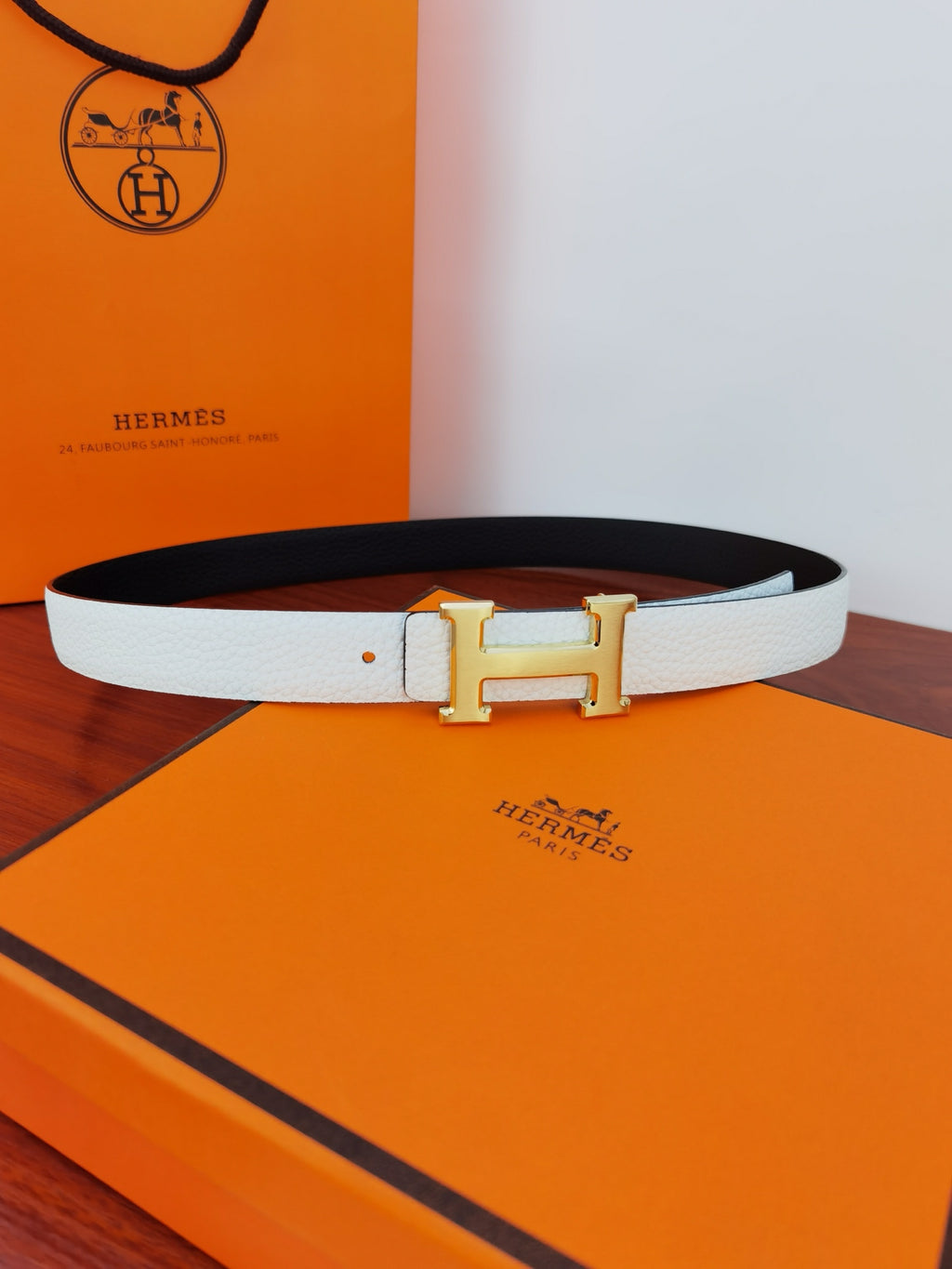 Hermes reversible belt with light white strap, dark reverse, and gold-toned H buckle