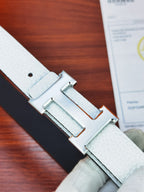 Hermes belt close-up of light white textured leather and silver rectangular buckle