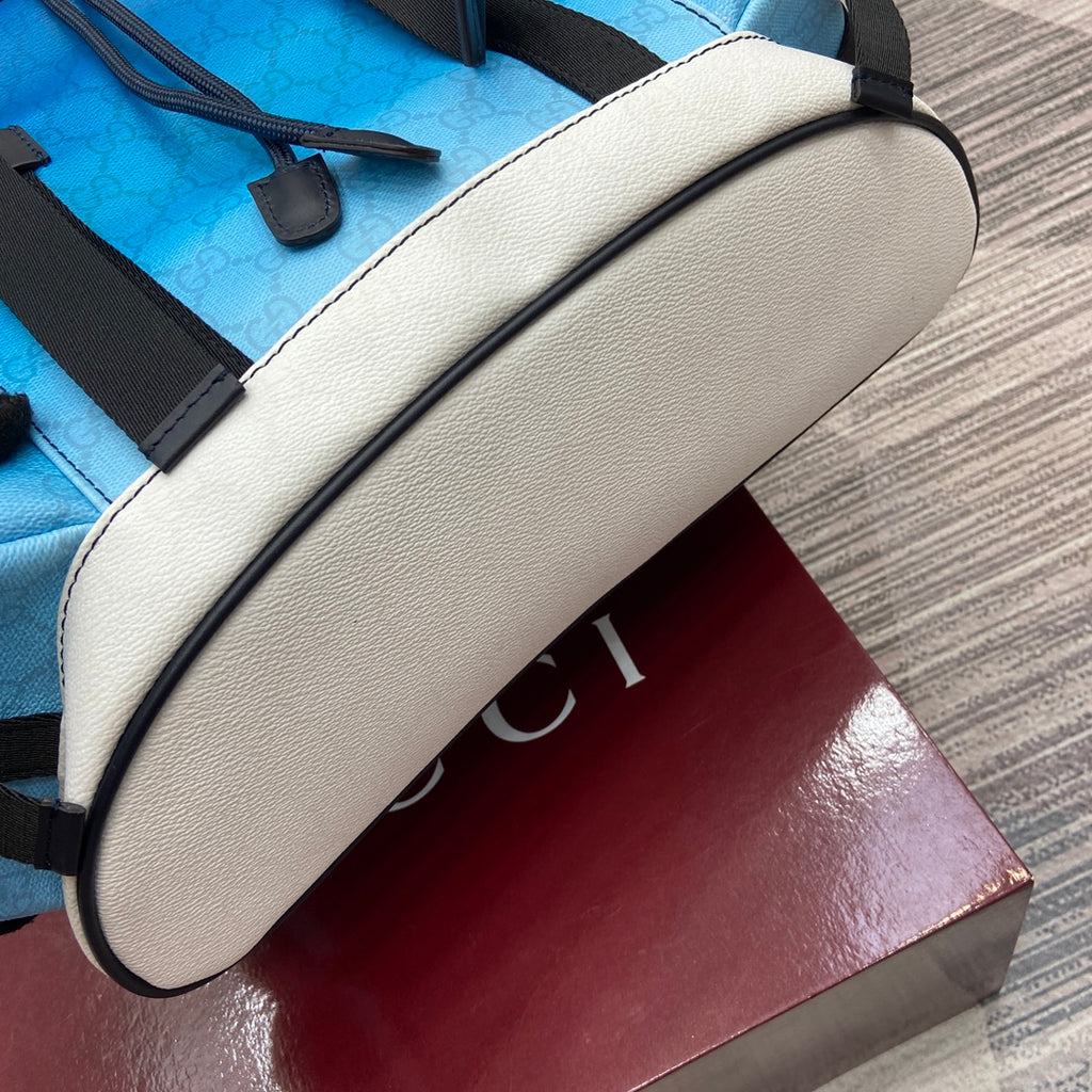 Gucci men’s backpack bottom corner with bright blue leather, black edging, and white trim