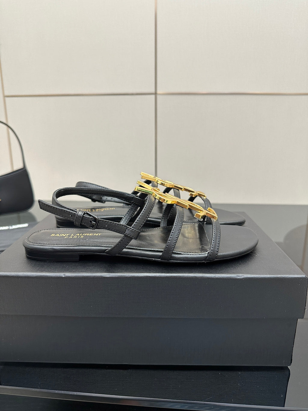 Black flat thong sandals with gold YSL logo on top straps