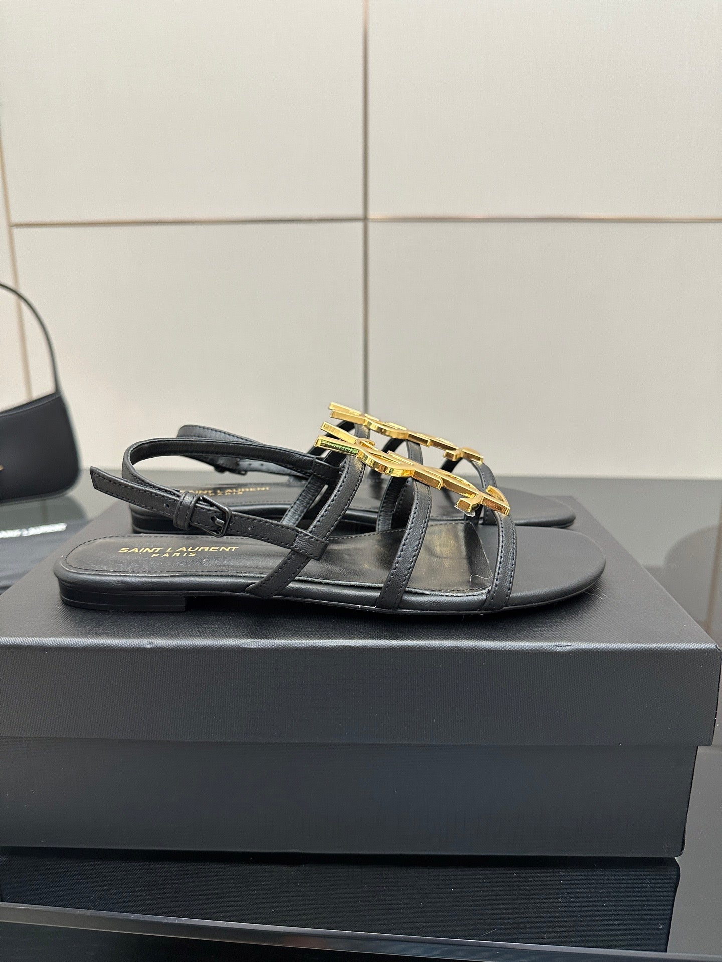 Black flat thong sandals with gold YSL logo on top straps