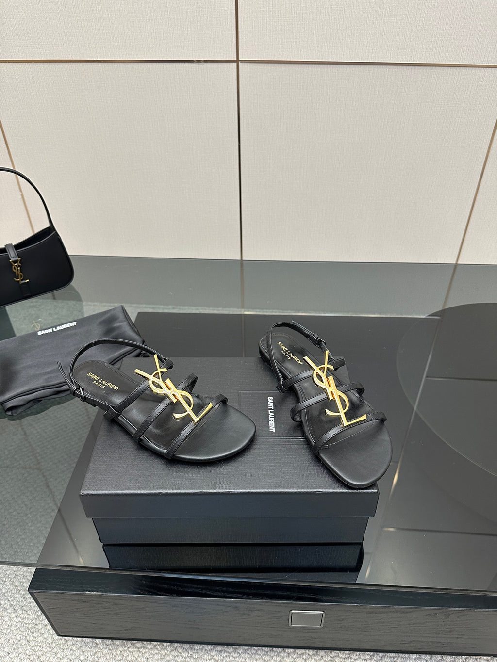 Pair of black thong sandals on a box, gold YSL logo detail