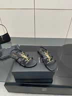 Pair of black thong sandals on a box, gold YSL logo detail