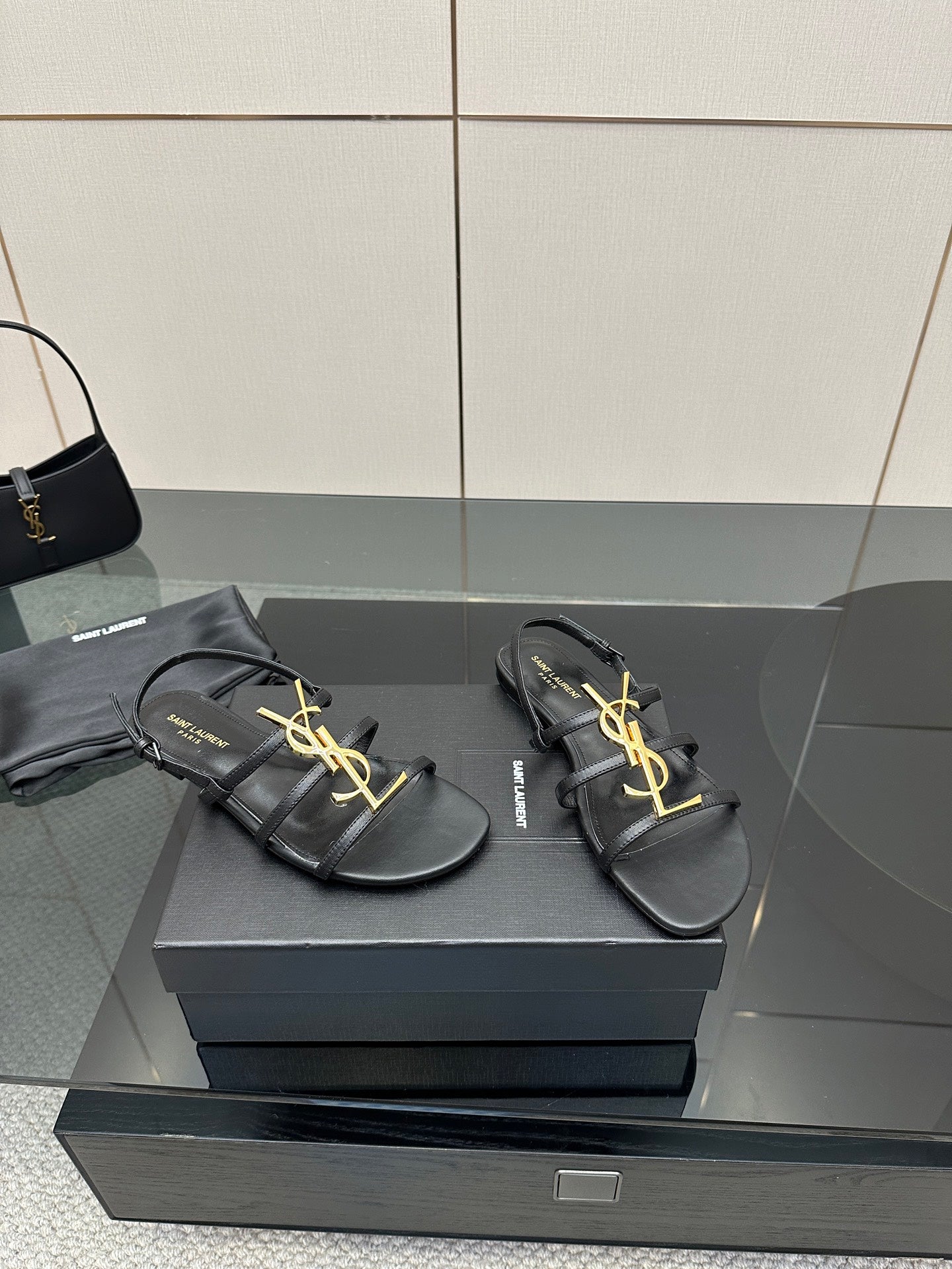 Pair of black thong sandals on a box, gold YSL logo detail