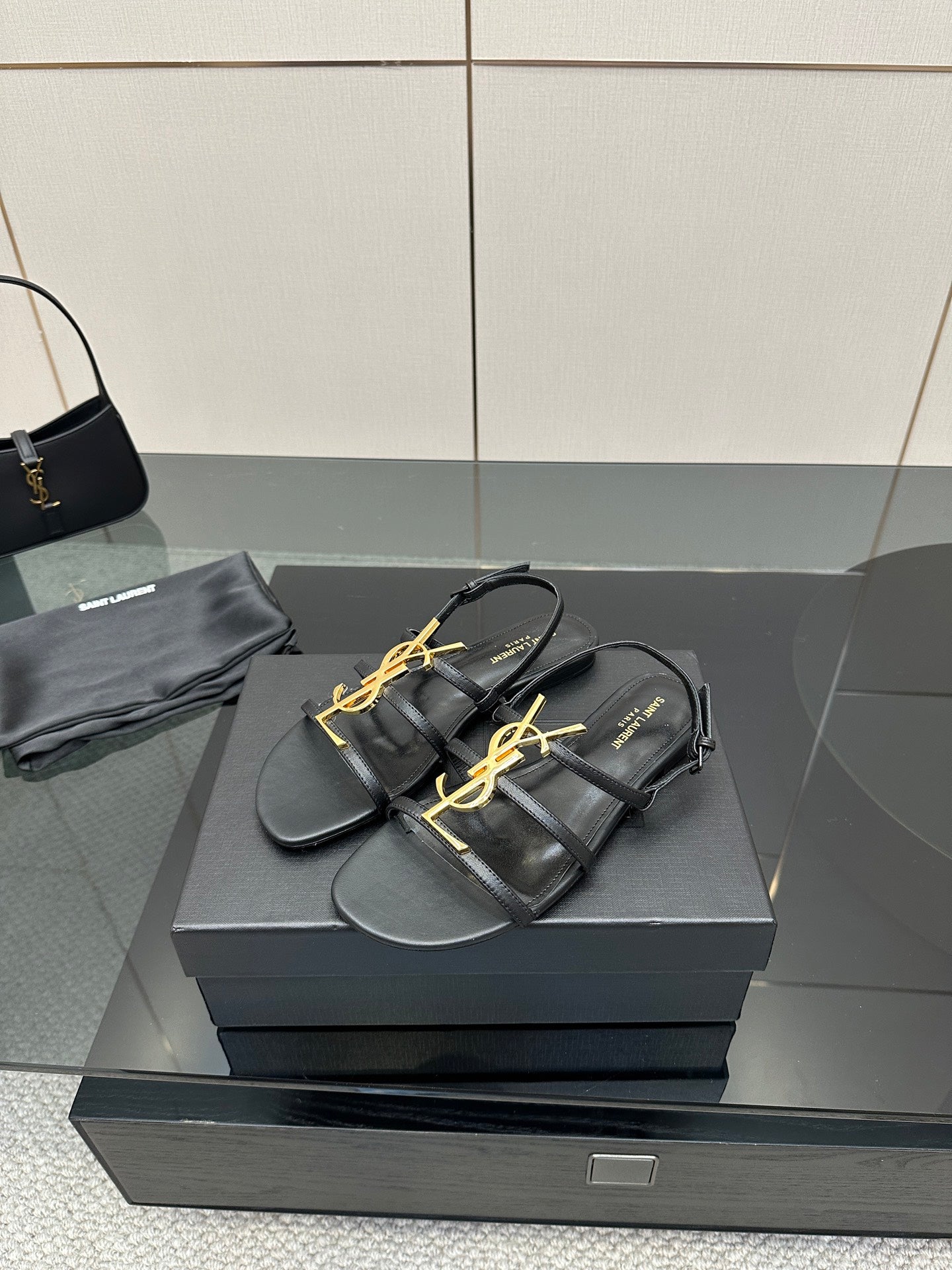 Black thong sandals with gold YSL emblem and flat sole