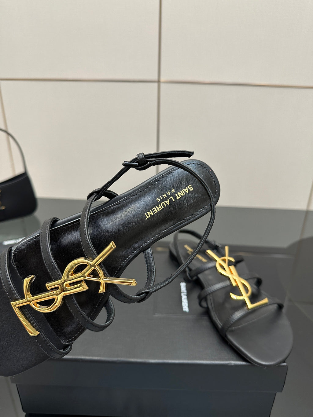 Black thong sandal showing gold YSL logo and inner text label