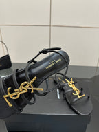 Black thong sandal showing gold YSL logo and inner text label