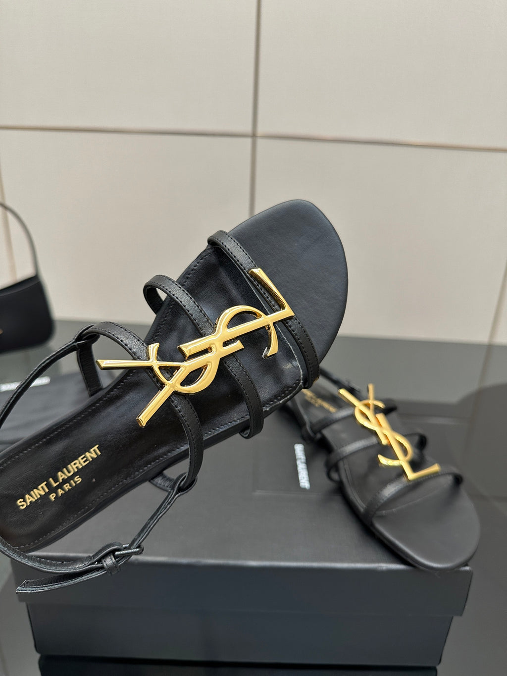 Close view of black YSL thong sandals with gold logo on upper