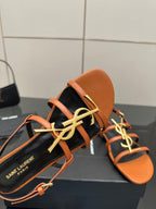 Women's sandal close-up: orange straps over black footbed with SAINT LAURENT logo detail