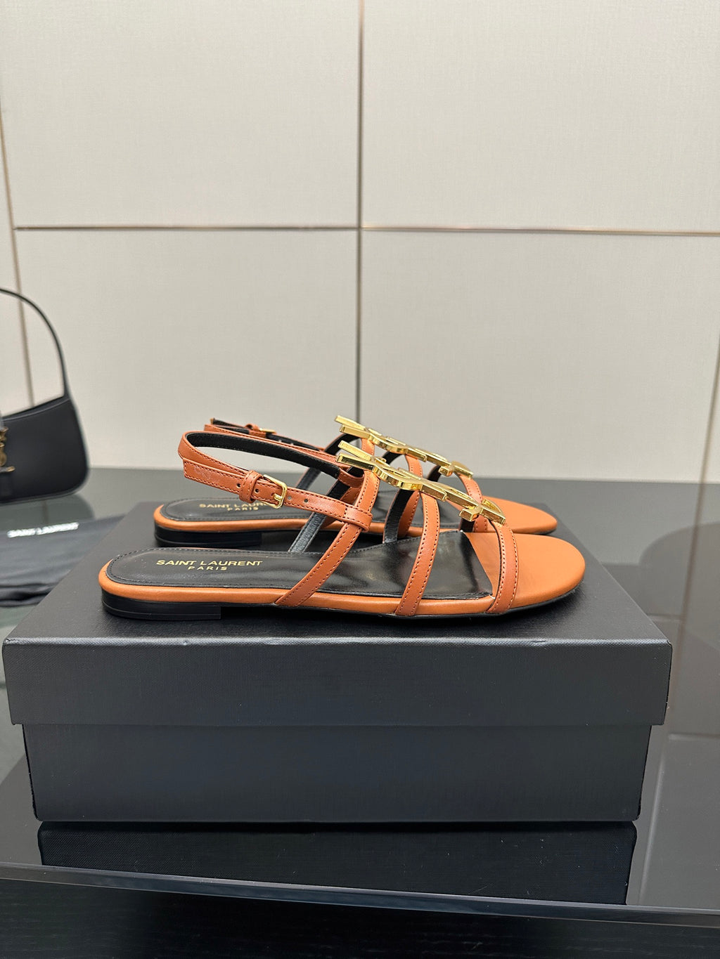 Women's flat slide sandals in orange with black straps and gold-tone logo hardware