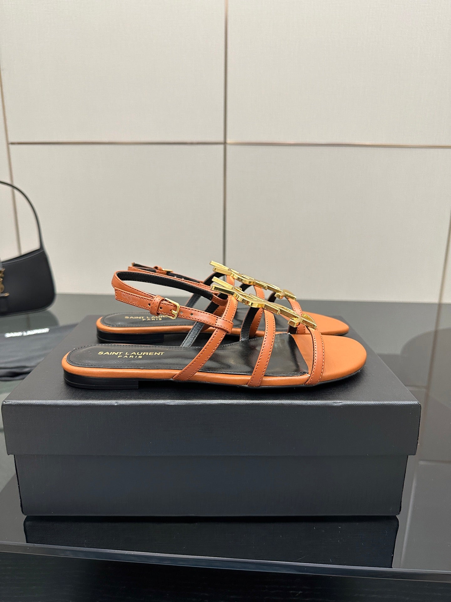 Women's flat slide sandals in orange with black straps and gold-tone logo hardware