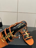 Women's sandal close-up: black footbed with orange straps and gold-tone SAINT LAURENT logo