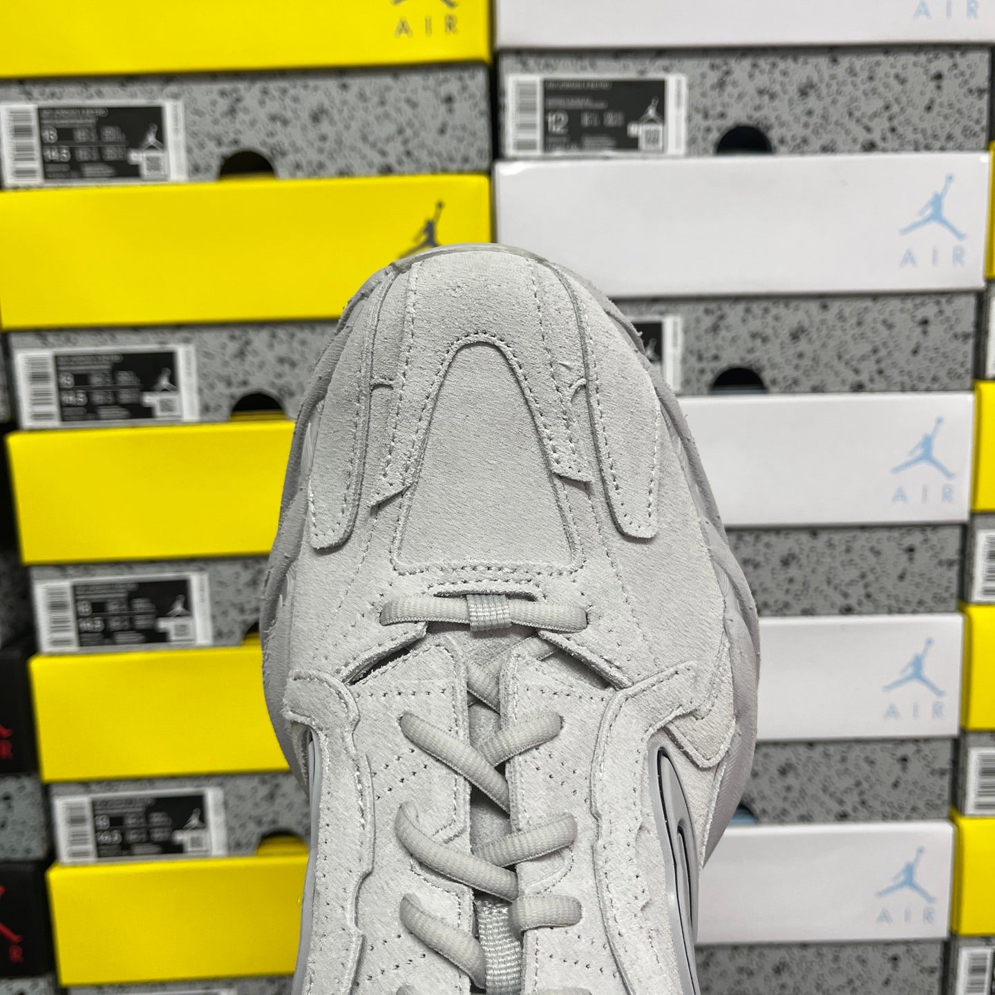 Light gray unisex running sneaker front view with lace-up and textured panel details
