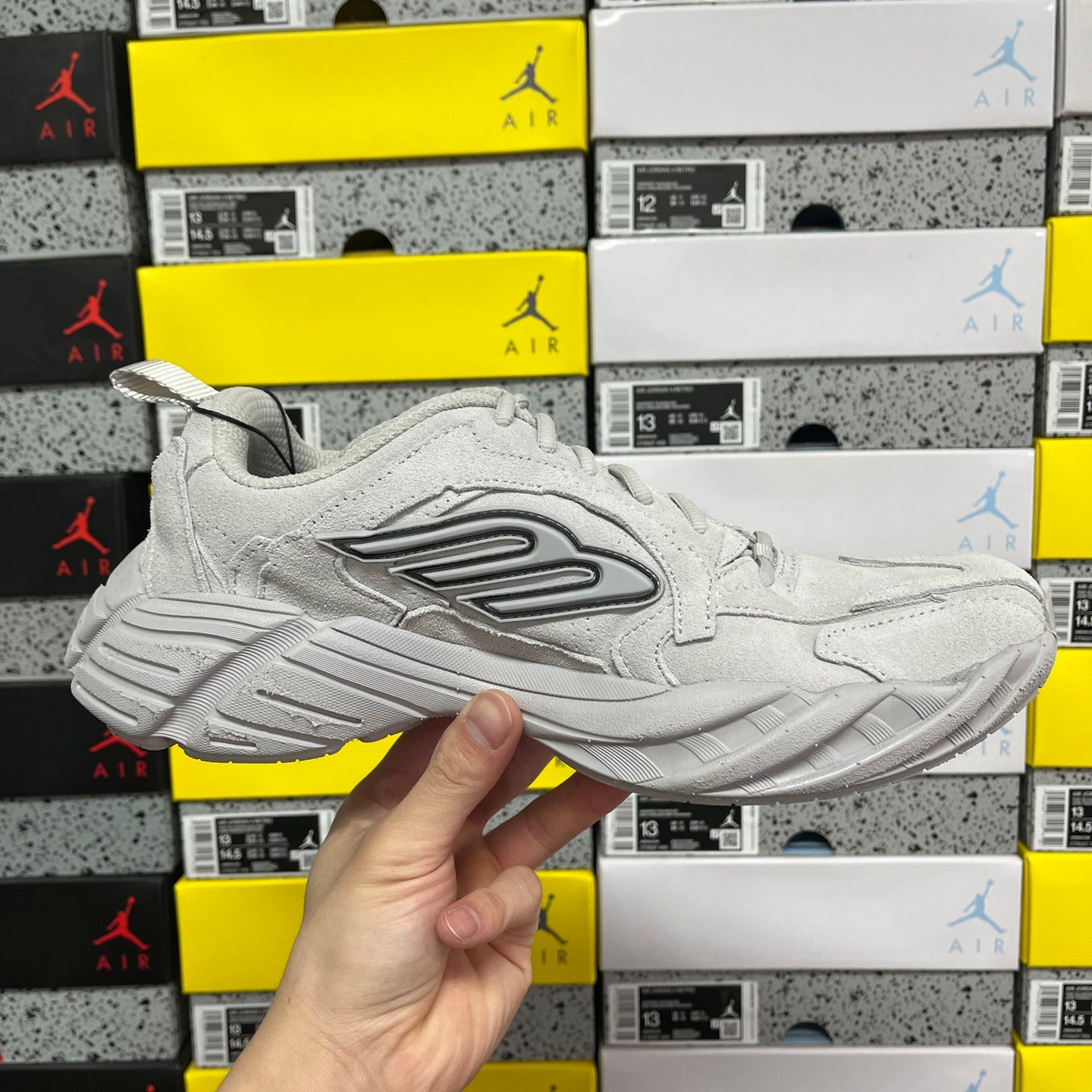 Light gray unisex running sneaker angled side view with lace-up and logo panel