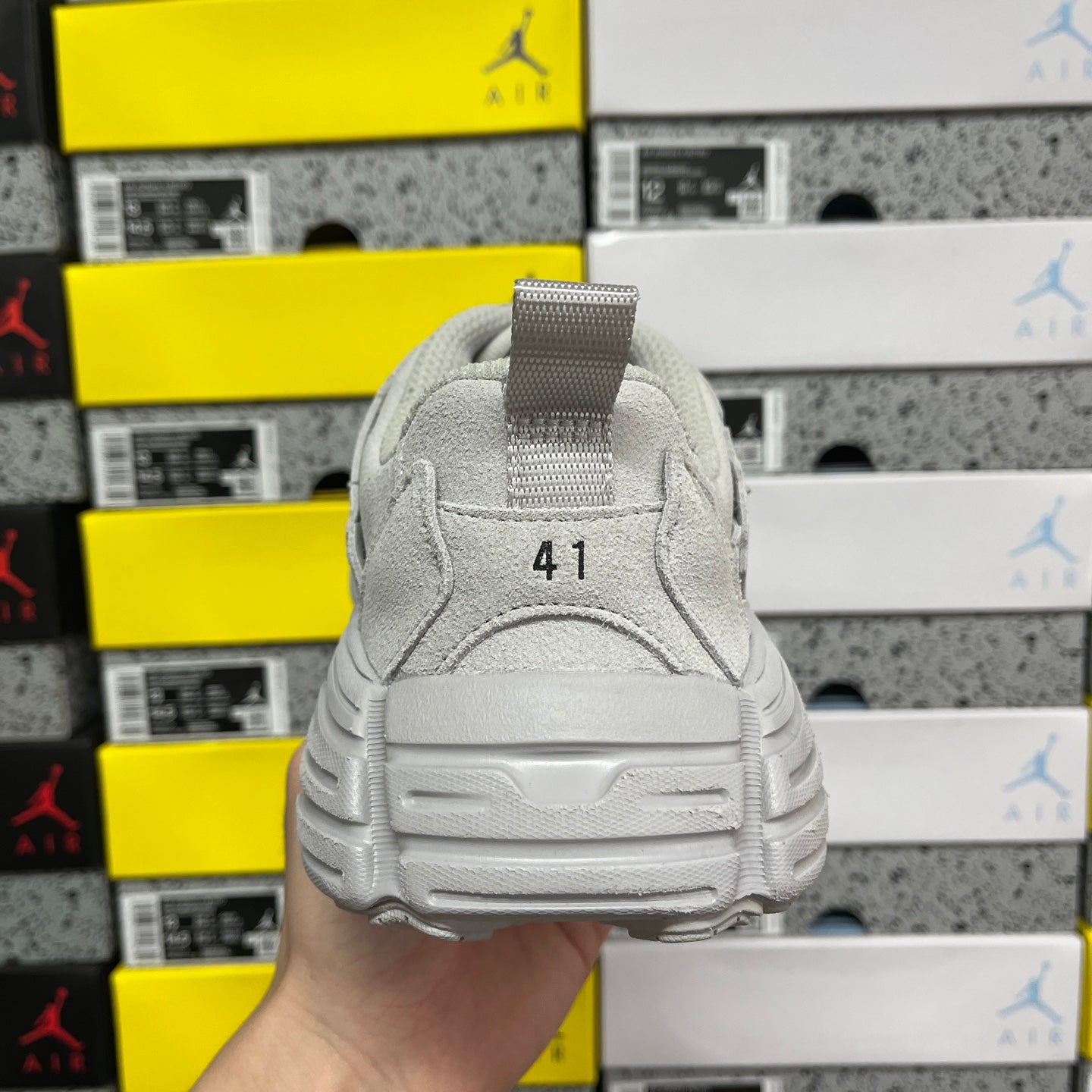Light gray unisex running sneaker heel view with strap tab and cushioned sole