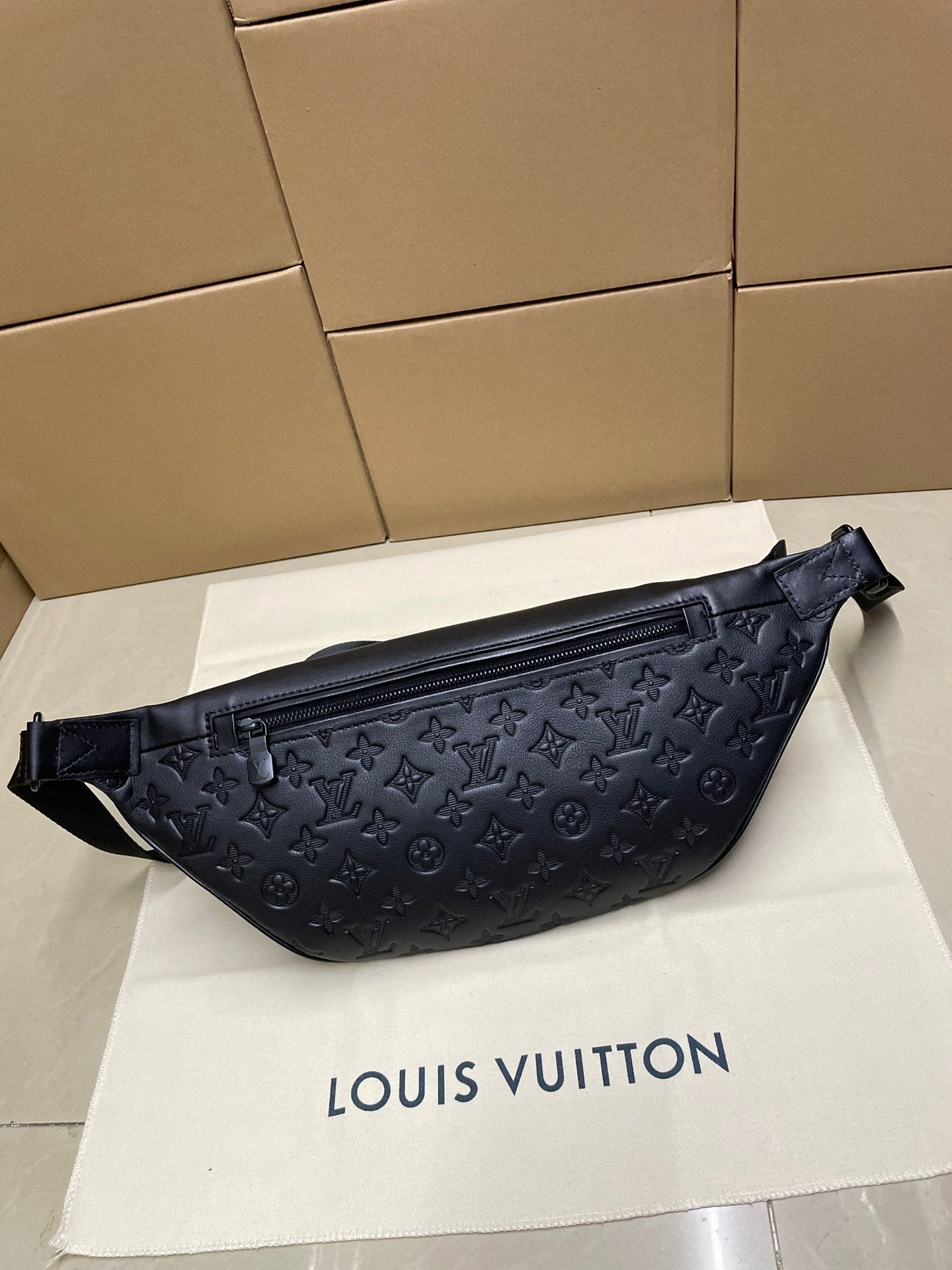 Men’s Louis Vuitton monogram sling bag in dark navy, front view with zip pocket