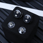 Four silver-tone stud earrings with black circular backs and logo center