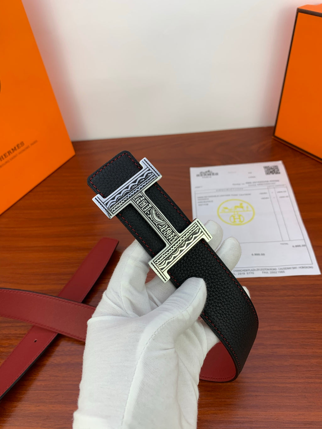 Hermes belt, black textured strap with ornate silver H buckle, red lining detail