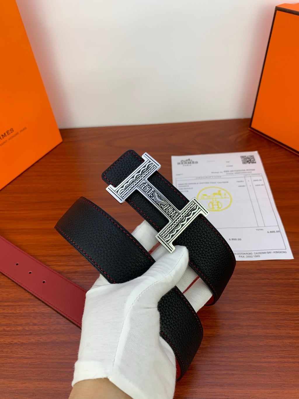 Hermes belt viewed from side: black textured leather with silver H buckle and red lining