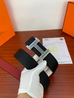 Hermes belt viewed from side: black textured leather with silver H buckle and red lining