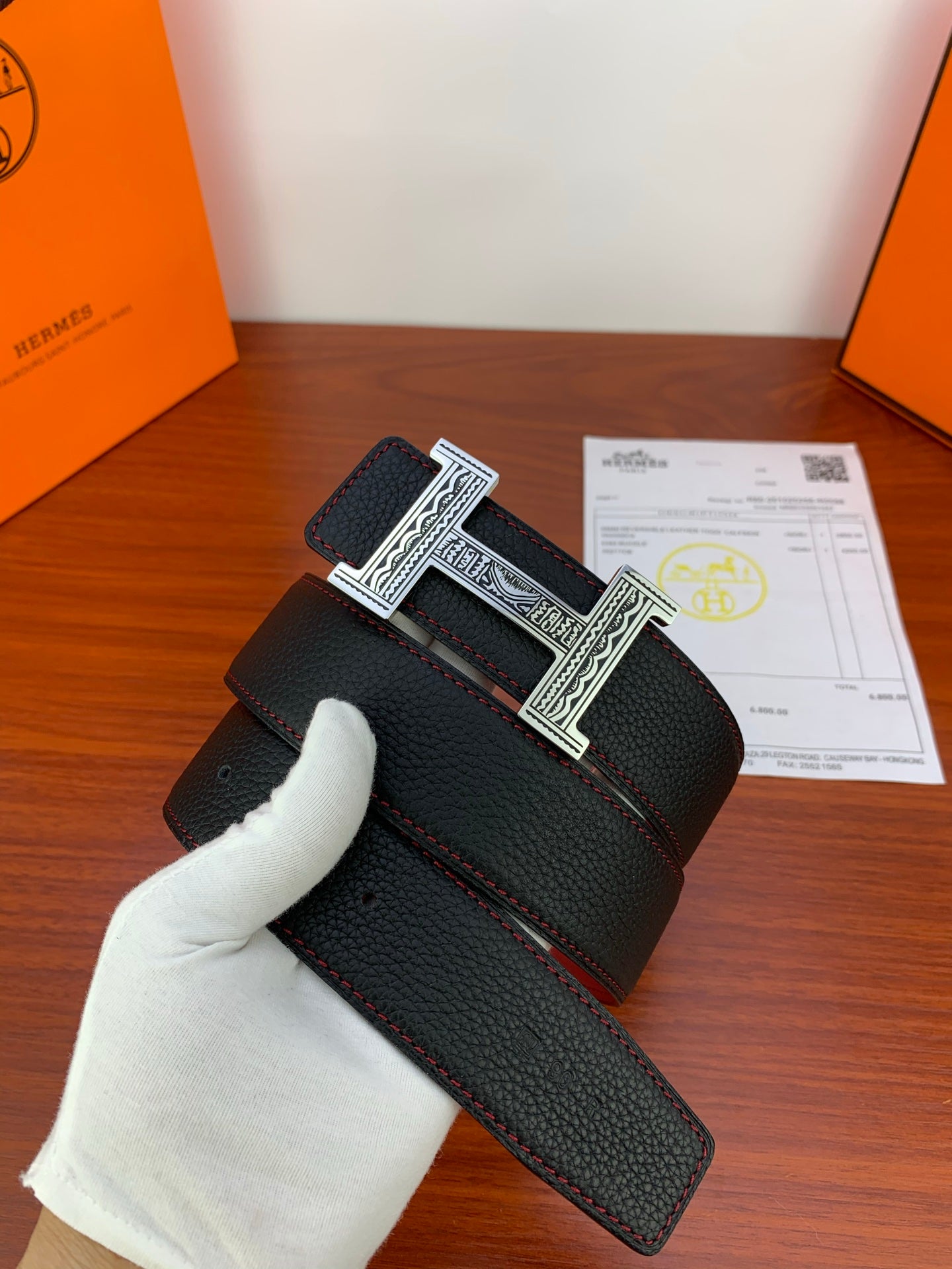 Hermes belt with black textured leather and silver-tone engraved H buckle, red underside