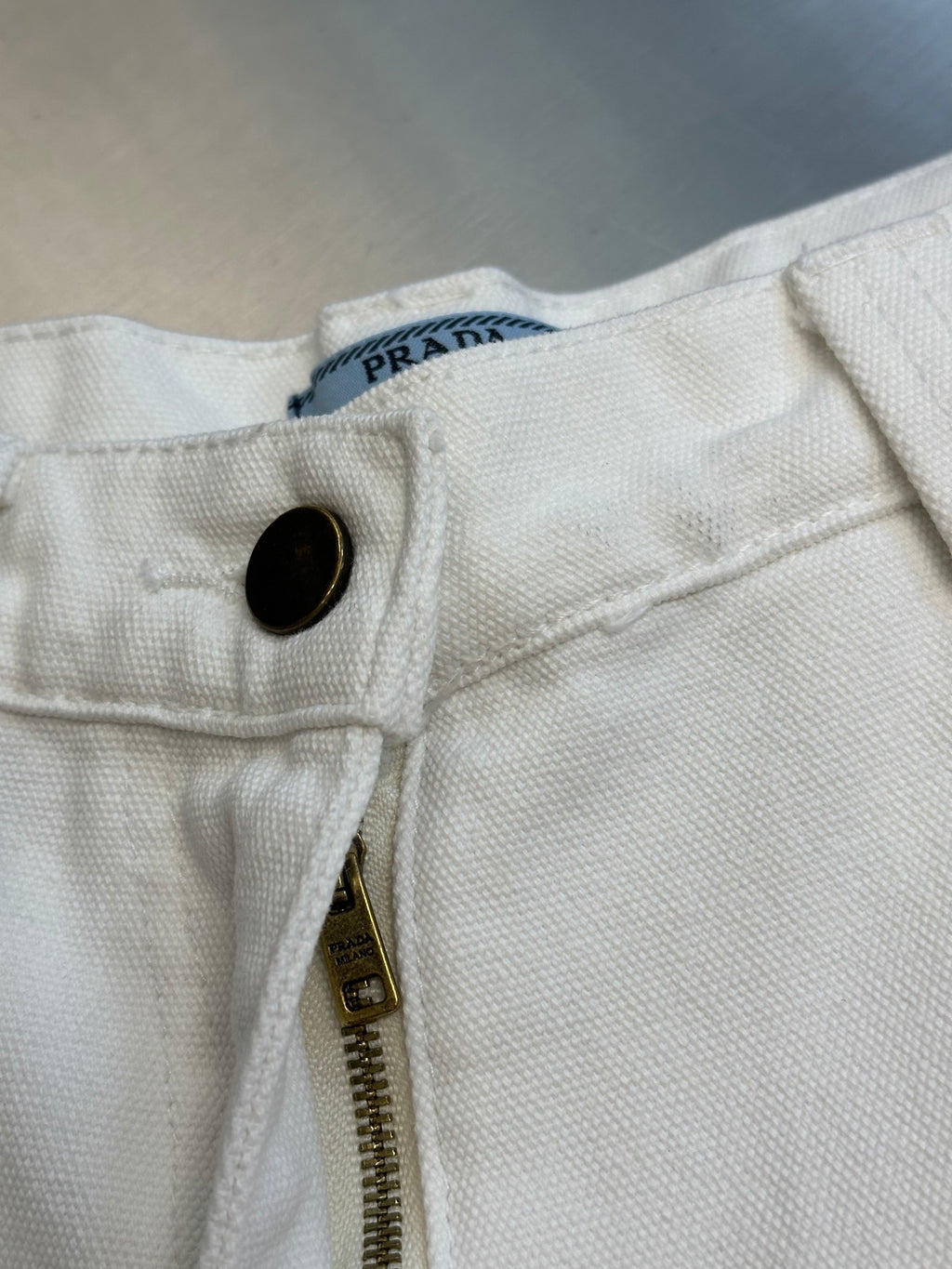 Off-white cargo pants waistband with PRADA-style logo tag and button