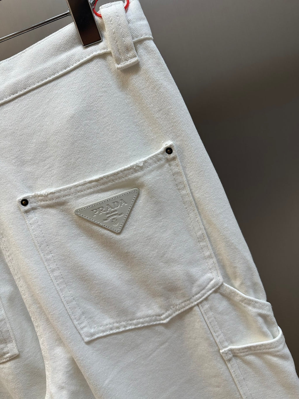 Prada off-white cargo pants with stitched triangular logo patch on patch pocket