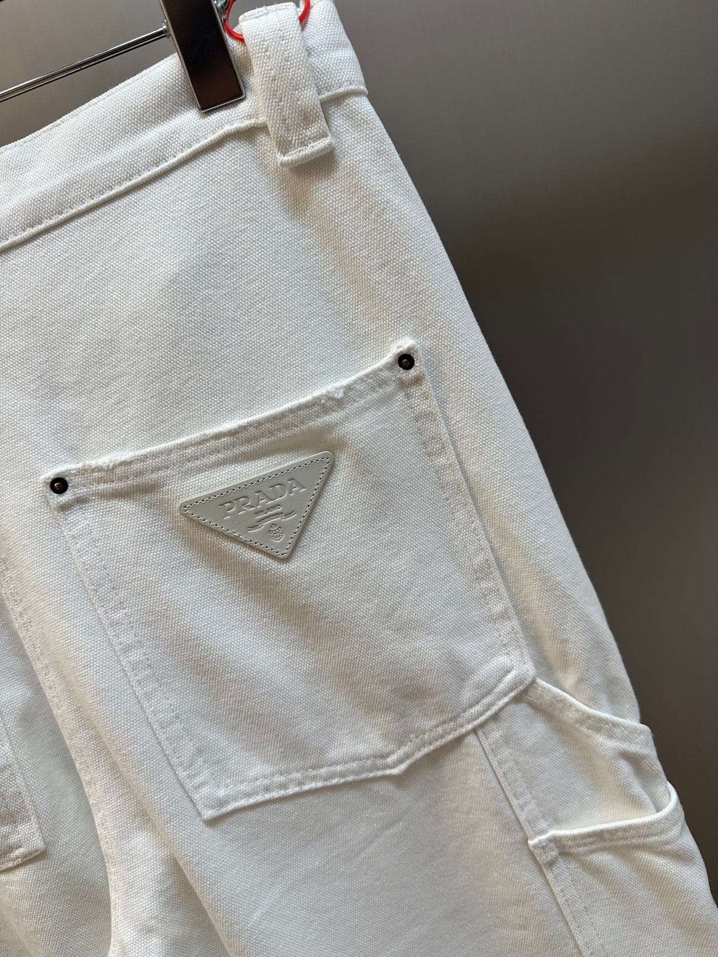 Prada off-white cargo pants with stitched triangular logo patch on patch pocket