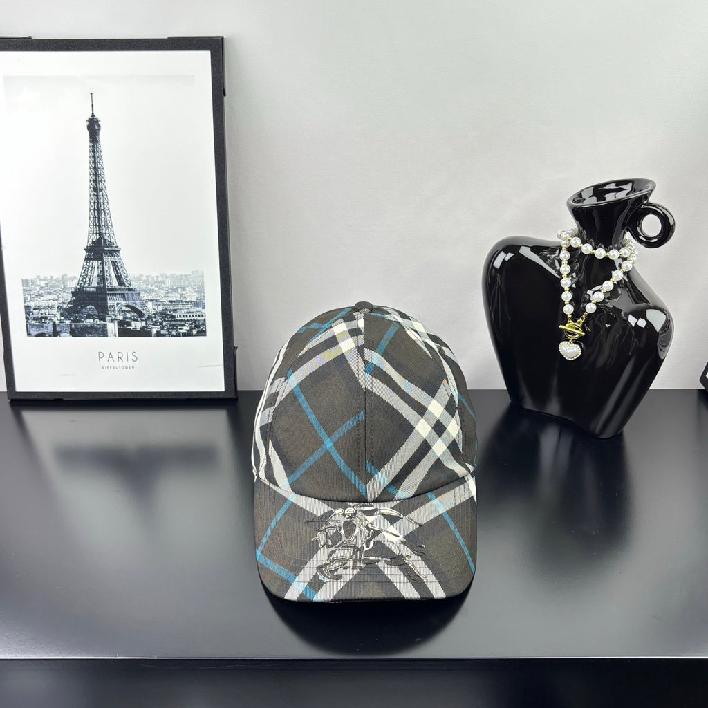 Burberry cap in dark gray, white, and blue plaid with crest emblem on front.