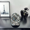 Burberry cap in dark gray, white, and blue plaid with crest emblem on front.