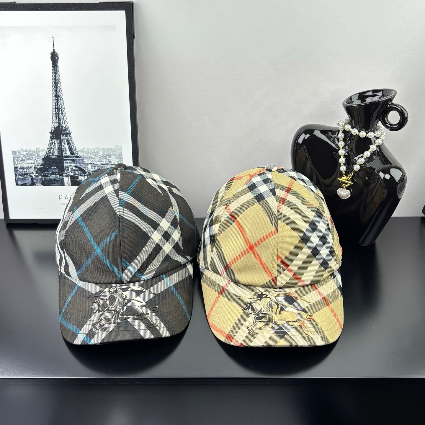 Pair of Burberry caps: one dark gray/blue plaid, one beige/cream plaid, each with crest emblem.
