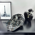 Burberry cap in dark gray and blue plaid with crest emblem near the front.