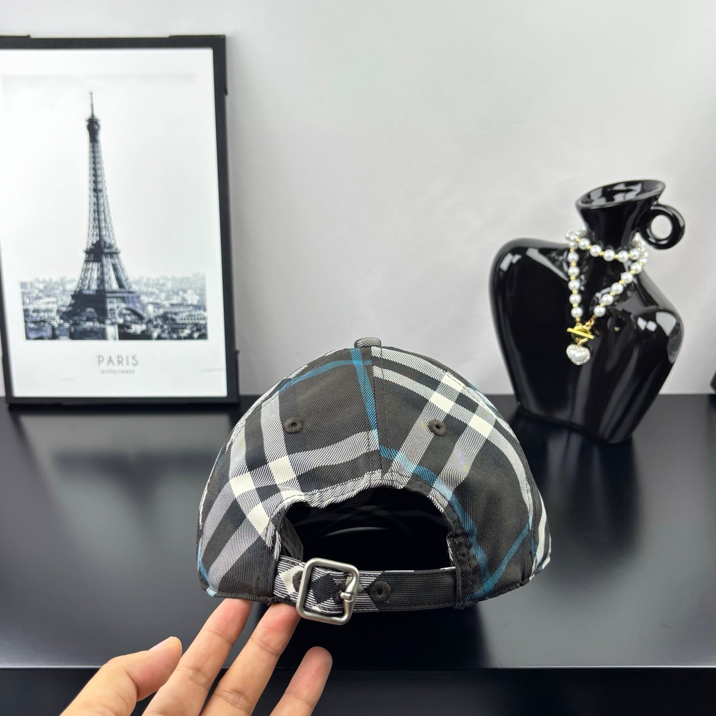 Burberry cap in dark gray and blue plaid with interior strap and buckle at back.