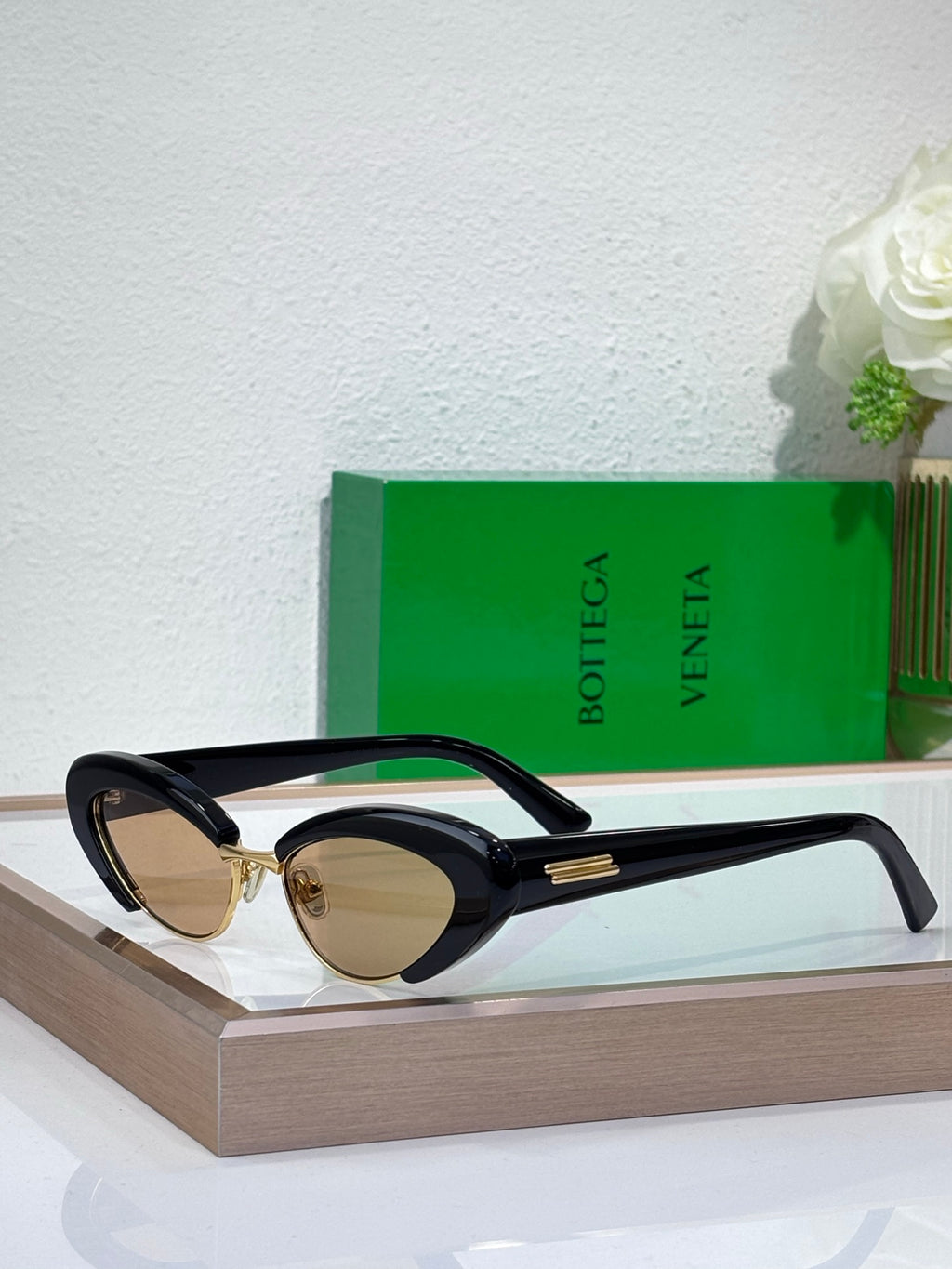 Bottega Veneta sunglasses with black frames, oval dark lenses, and gold-tone bridge