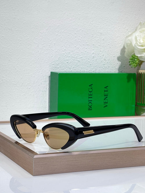 Bottega Veneta sunglasses with black frames, oval dark lenses, and gold-tone bridge